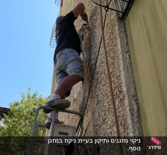 טכנאי מתקין מזגן על קיר חיצוני של בניין